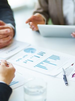 Image of business documents, pen and glasses on workplace during meeting of partners